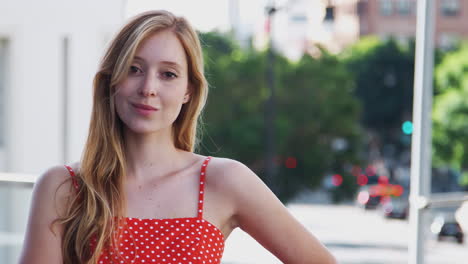 Portrait-Of-Smiling-Young-Businesswoman-Standing-Outside-Office-Building-With-City-Skyline-Behind