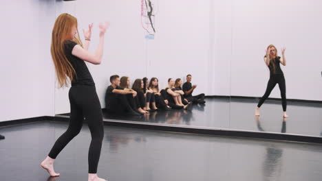 female dance student at performing arts school performs street dance for class in studio