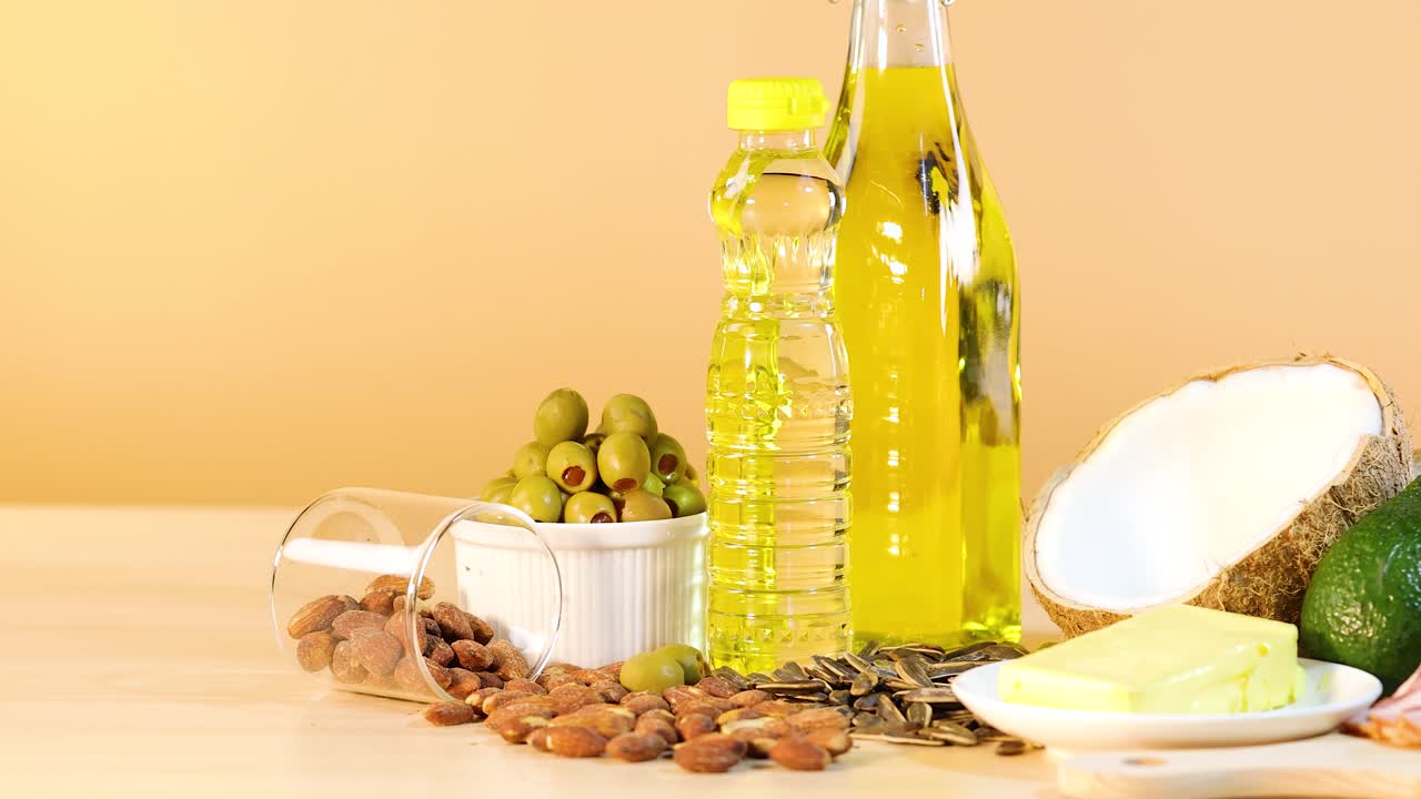 A vibrant arrangement of oils, nuts, and avocados on a wooden surface with warm lighting
