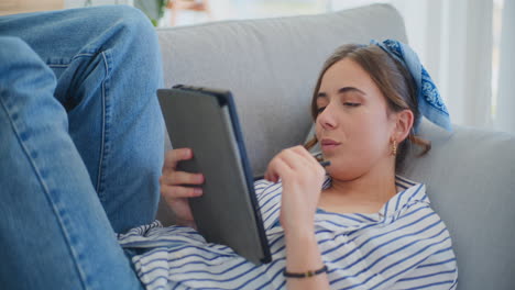 Mujer-Sonriente-Relajándose-En-El-Sofá-Mientras-Navega-Por-Internet