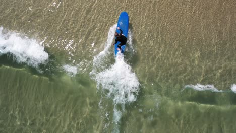 Topdown-of-Surf-professor-gives-little-push-while-surf-student-catching-small-shore-wave