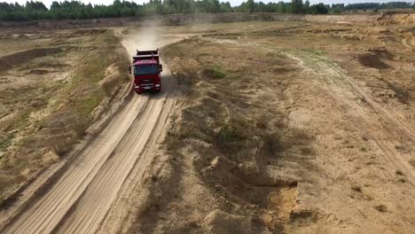 red dump truck driving through a sand quarry