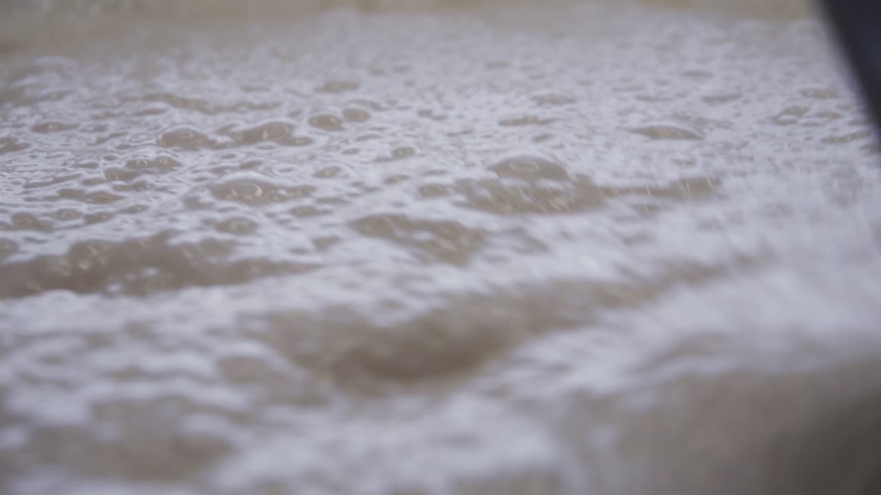 팬케이크를 만들기 위해 그릇에 거품이 이는 효모 제품 덩어리를 숟가락으로 섞습니다.