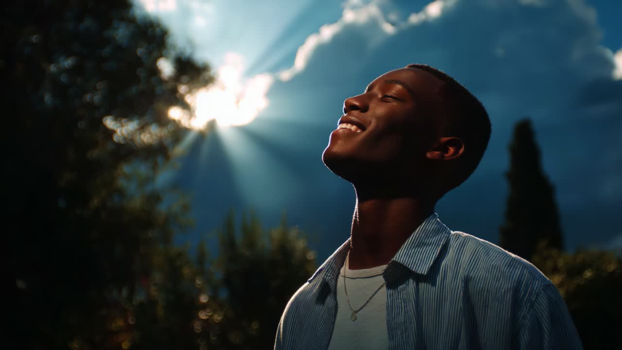 A young man experiencing a moment of serene bliss as beams of sunlight cut through ominous clouds, capturing a sense of hope and tranquility amidst the contrasting beauty of nature