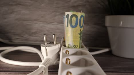 closeup shot of money and a socket showing the high energy price concept.