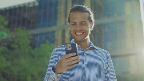 young man reacts to smartphone with surprise and joy