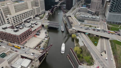 Aerial-overview-of-vessels-moving-though-open-bridges-on-the-Chicago-river,-in-USA