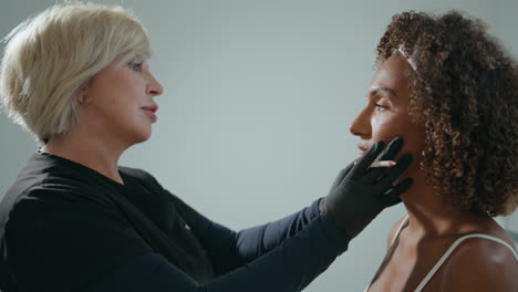 cosmetóloga consultando a una mujer cliente en un salón de belleza. médico examina la piel de la cara