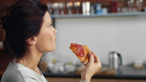 woman biting slice of pizza at home. hungry girl eating pizza from box.