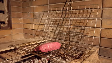 handheld shot of man placing steak onto charcoal bbq grill - seasoning with salt - pepper at night