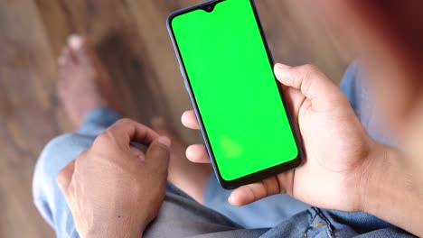 persona que sostiene un teléfono inteligente con una pantalla verde