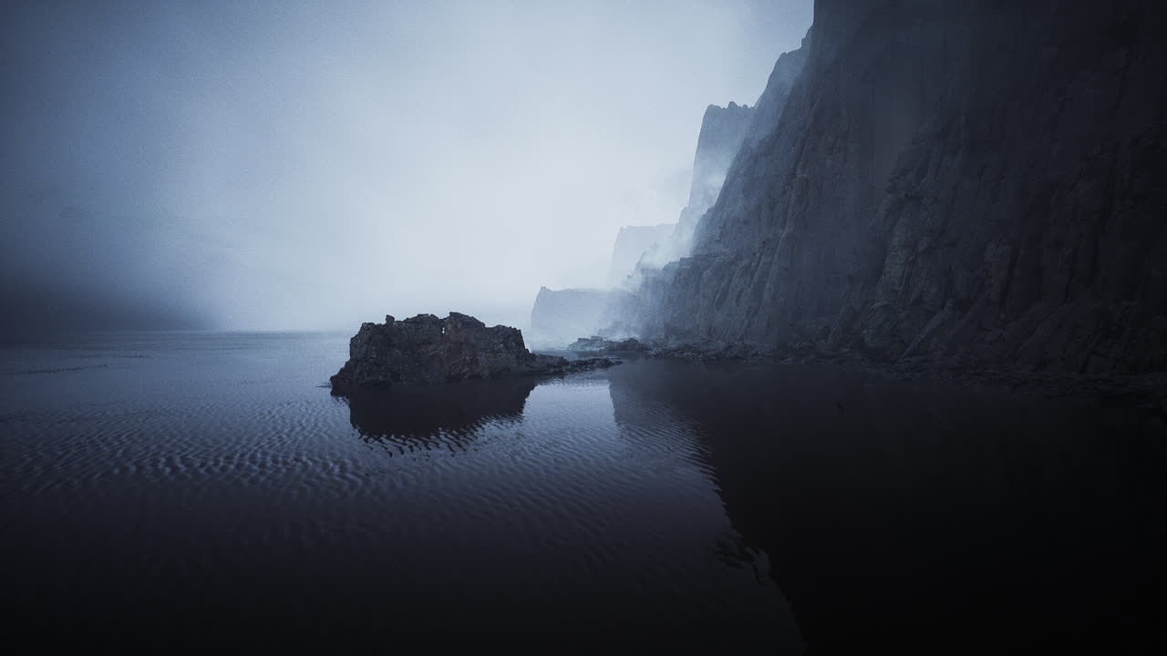 Misty shoreline with rock formations and calm water at dawn