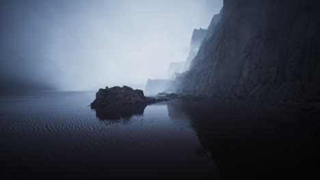 misty shoreline with rock formations and calm water at dawn