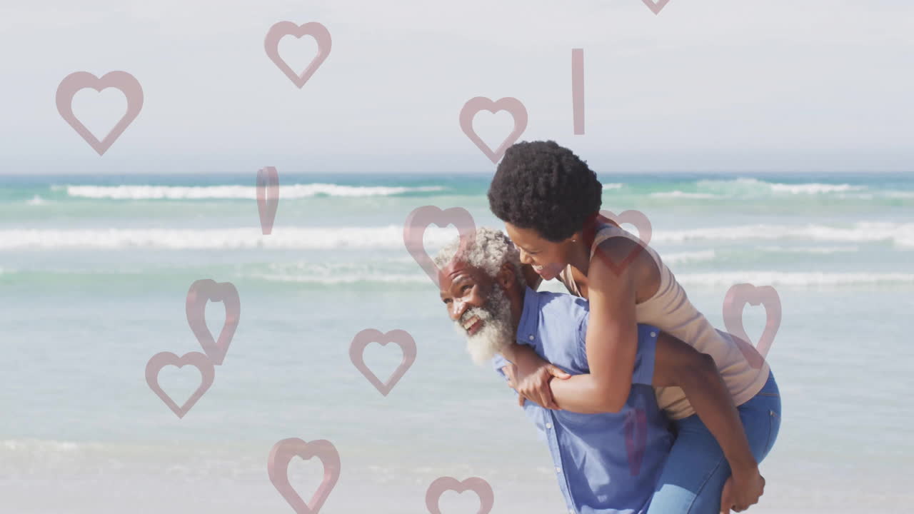 Elderly man giving piggyback ride to woman on beach with heart animation