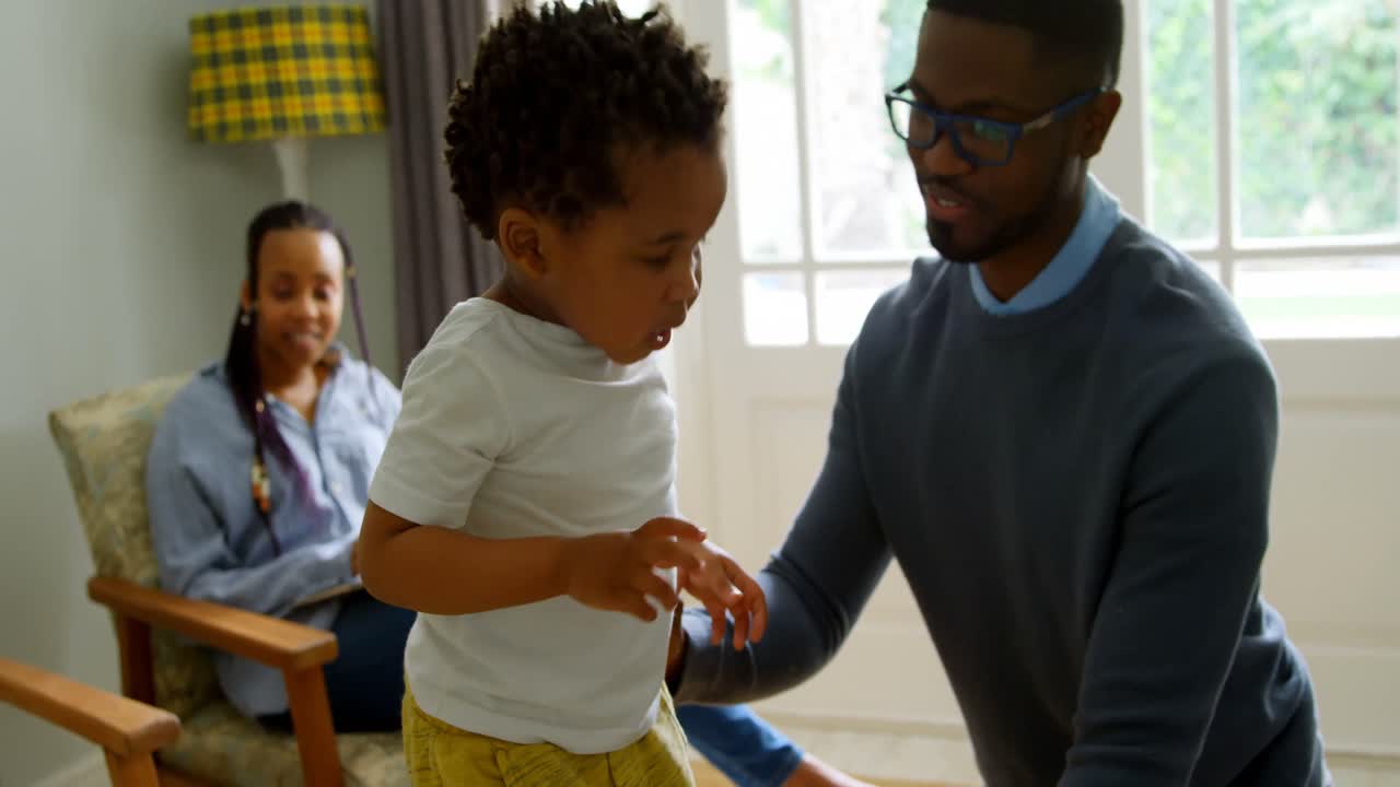 vista frontal de un joven padre negro jugando con su hijo en la vida de una casa cómoda 4k