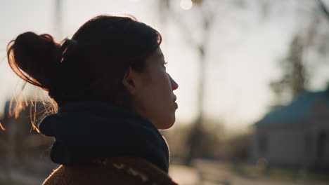 close-up of a girl walking with a tearful expression, capturing a moment of deep contemplation and sorrow. the soft backlighting of the sunset adds a reflective and emotional atmosphere to the scene