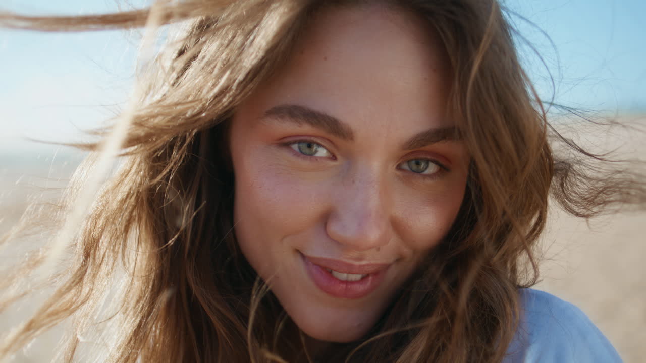 Portrait woman posing beach. Windy hair girl looking at camera at sandy shore