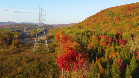 High-power-lines-surrounded-by-colorful-autumn-forest,-aerial-drone-view