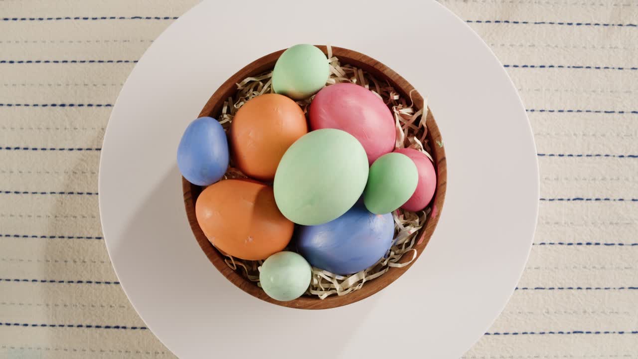 счастливый пасхальный праздник. цветные яйца в миске с верхним видом вращающимся. подготовка к пасхе, окраска и украшение яиц. христианское празднование, семейные традиции.