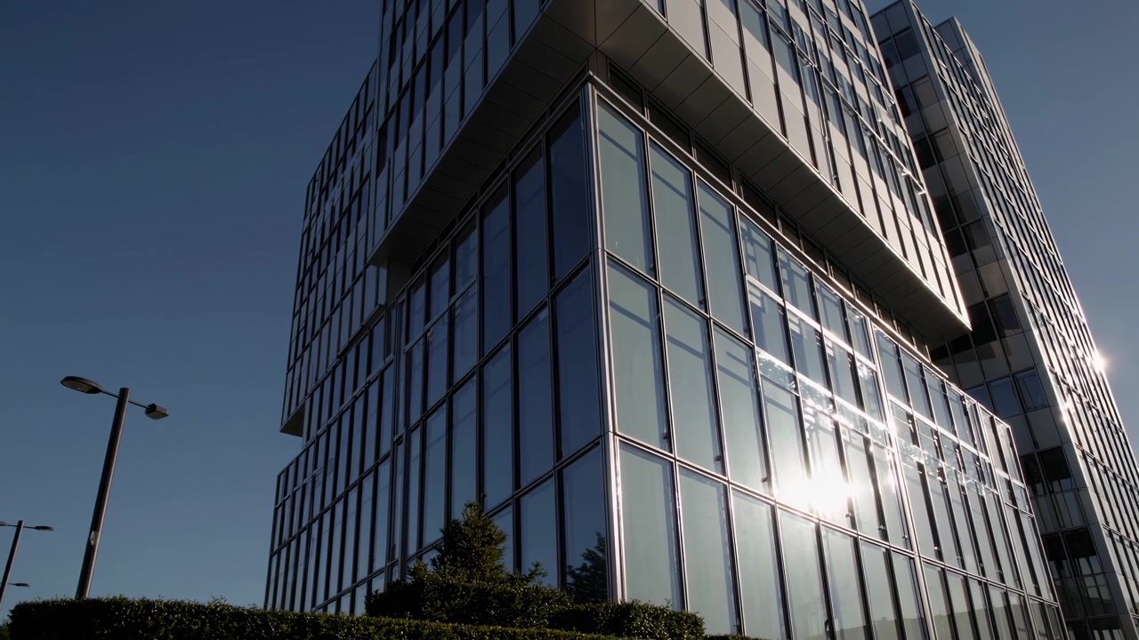 Exterior de un moderno edificio de oficinas de cristal bajo un cielo azul claro.
