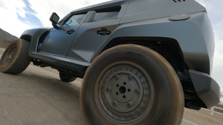 Ripresa dal drone FPV dal basso di un pick-up nero che guida veloce su strada.