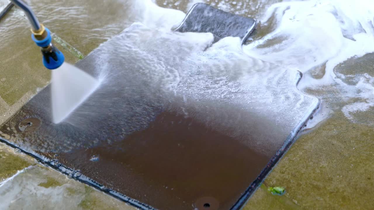 Rinsing small car foot with pressure washer and blue jet wash nozzle - close up