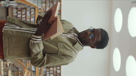 Hombre-Afroamericano-Leyendo-Un-Libro-En-La-Biblioteca