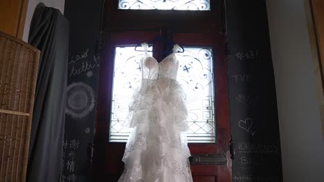 beautiful white long wedding dress hanging above the door inside traditional and modern italian home