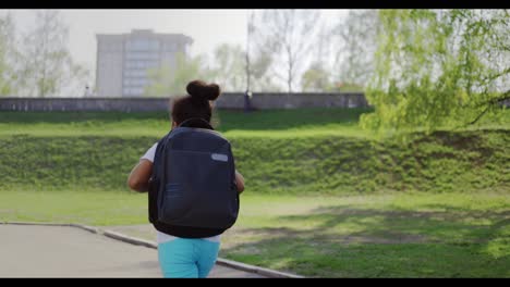 girl with backpack walking in park