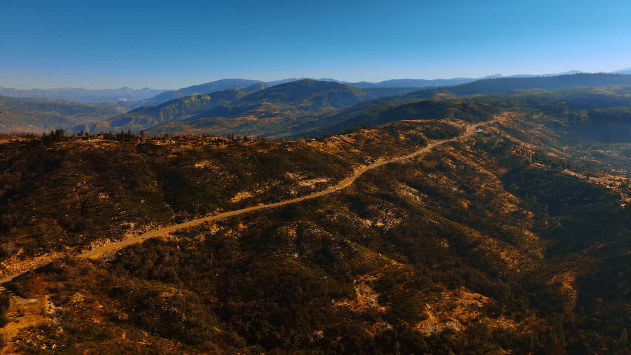 Rising above the tops of mountains range on clear sunny day. Beautiful panorama of Sierra National Forest, USA from drone footage.