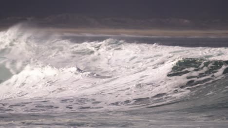 Surfer-finishes-the-ride-by-jumping-over-the-wave,-where-jetski-driver-is-waiting-to-take-him-to-safety