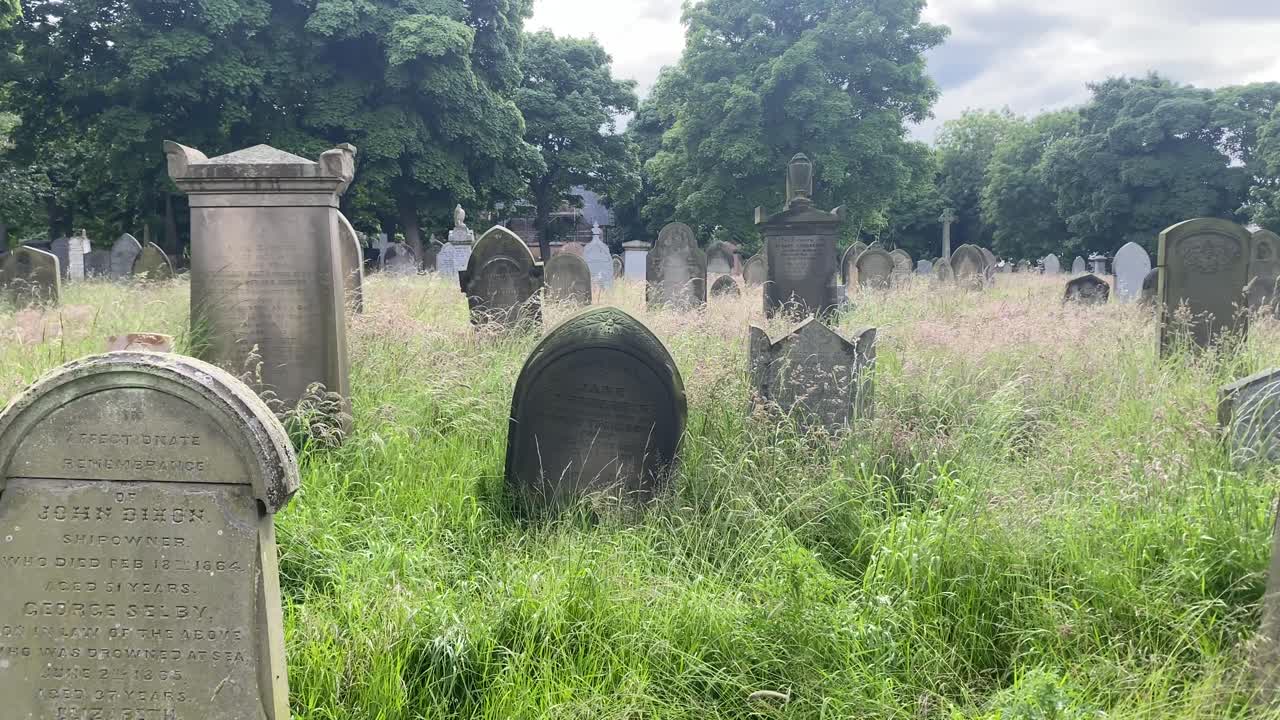Panning shot of overgrown graveyard or cemetery with old headstones. Daytime