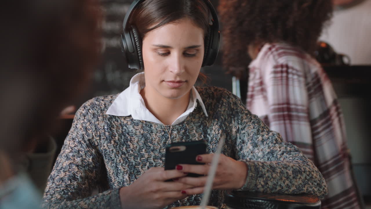 mujer joven usando un teléfono inteligente en un café enviando mensajes de texto navegando en línea disfrutando del entretenimiento de las redes sociales escuchando música en un restaurante ocupado