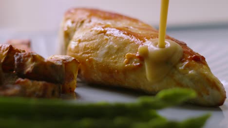 slow motion of peppercorn sauce being poured on pan fried chicken fillet with asparagus and parmentier potatoes. high quality restaurant food footage.