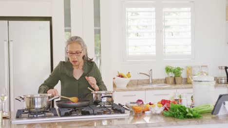 Happy-asian-senior-woman-using-tablet-and-cooking-in-kitchen