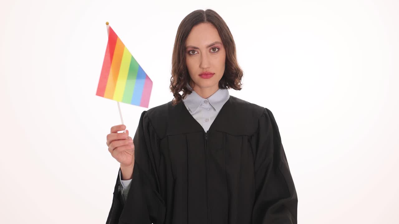 Giudice donna tiene una bandiera arcobaleno e alza un dito ammonitore per difendere.