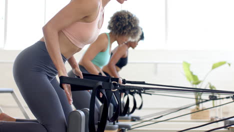 Tres-Mujeres-Practicando-Pilates-En-Máquinas-Reformadoras.