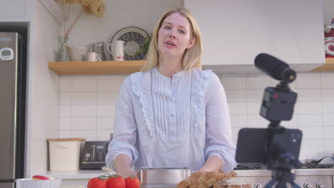 woman vlogging making social media video about food at home in kitchen on mobile phone - shot in slow motion