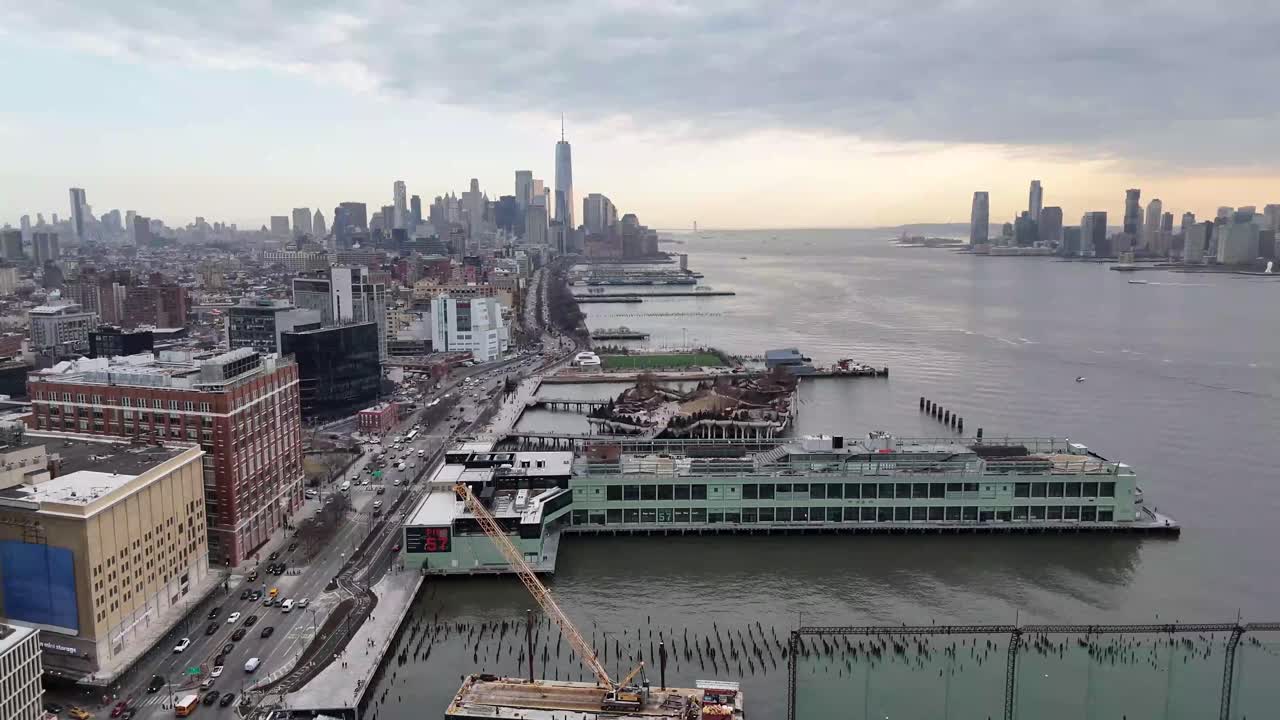 Horizontal drone side-tracking shot over 11th Avenue in New York along the Hudson River, capturing the city’s waterfront, skyscrapers, and dynamic Manhattan skyline with smooth lateral movement.