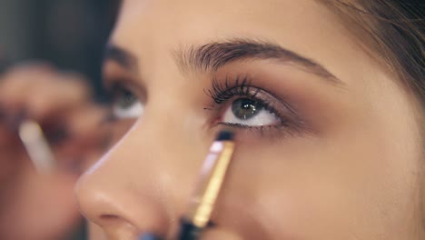 close up view of professional makeup artist's hands using makeup brush to apply eye shadows. slow motion shot