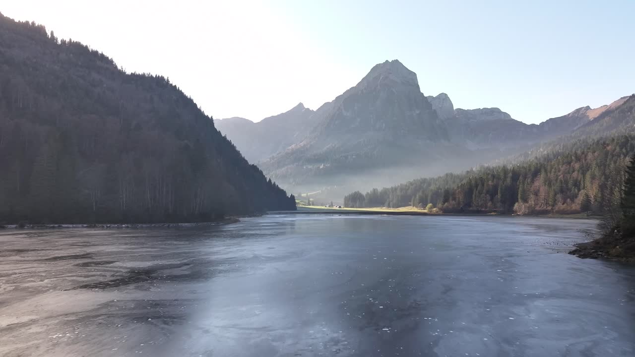 숲과 봉우리로 둘러싸인 얼어붙은 물이 있는 평온한 산 호수 풍경