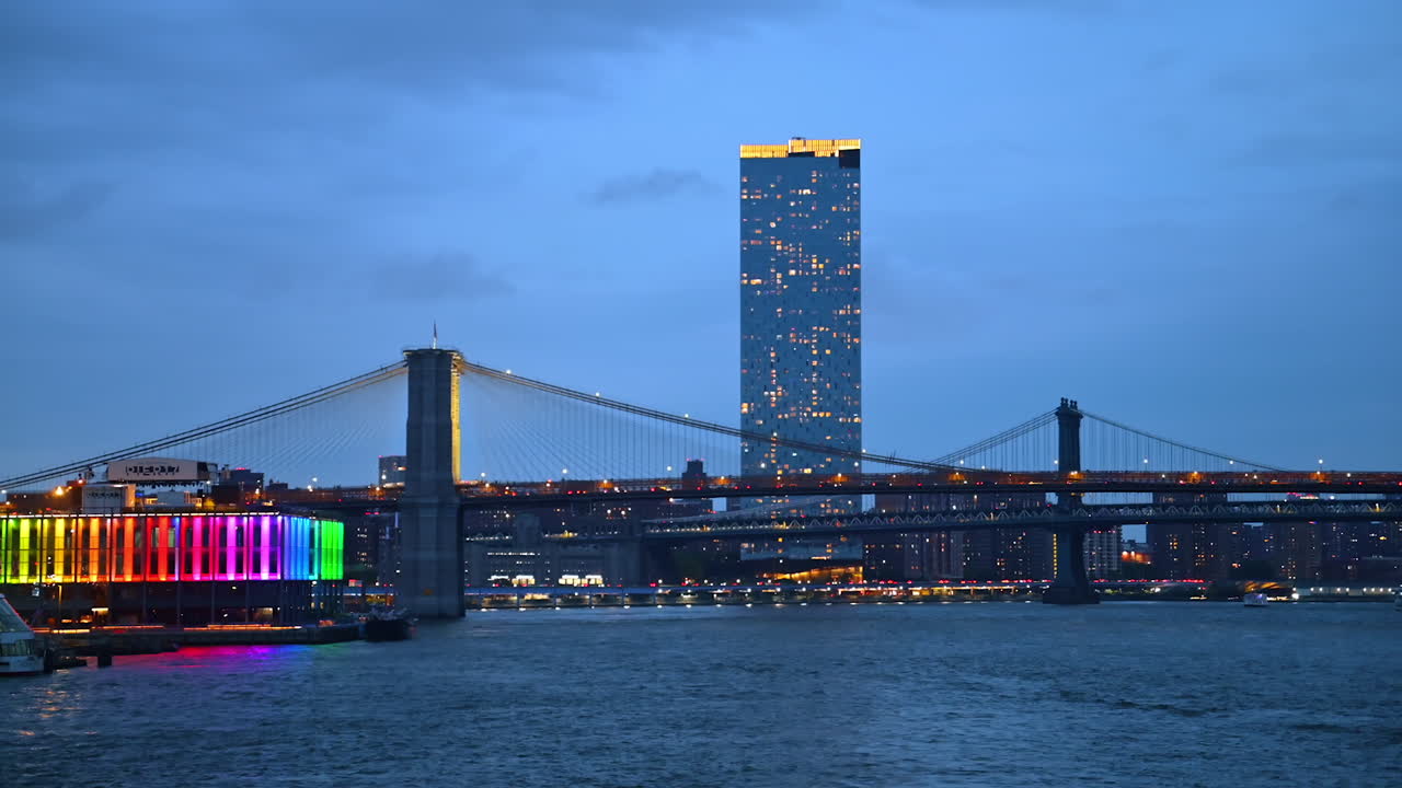 New York, USA, 1 August 2025: Brooklyn Bridge and skyline with colorful lights. The Brooklyn Bridge and Manhattan skyline glow with colorful lights over the East River at night