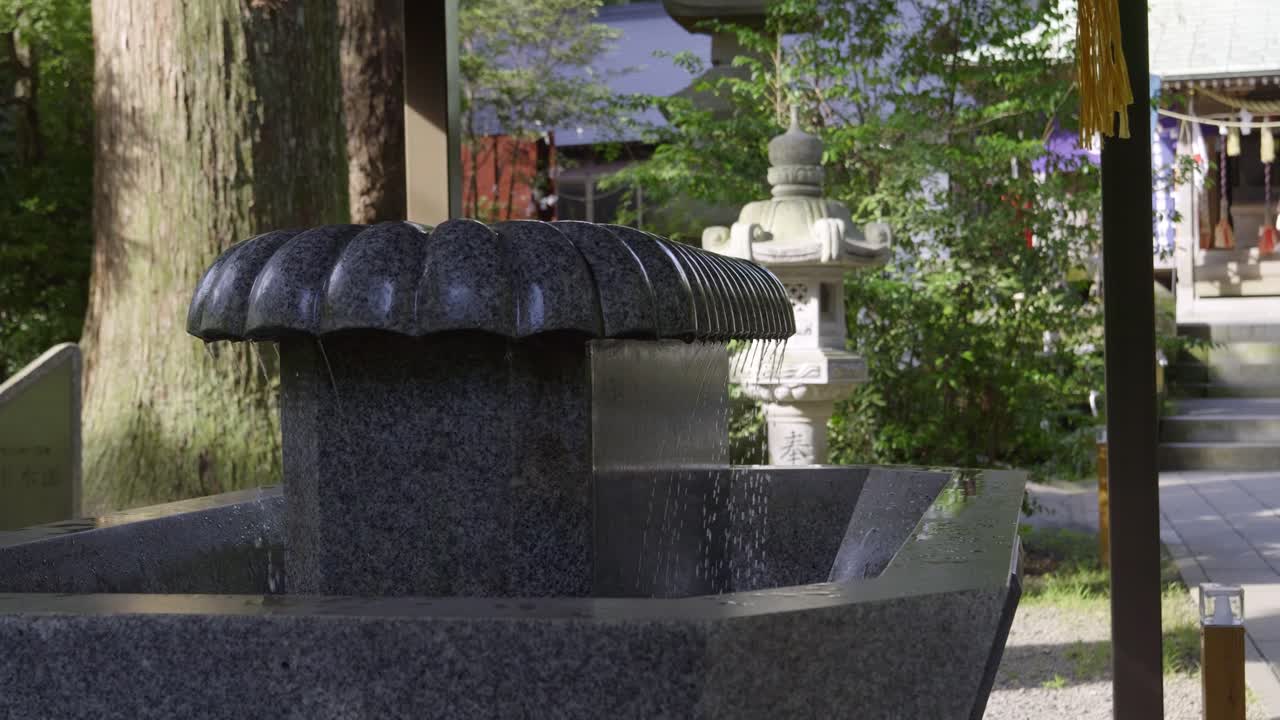 Close up over water basin at Japanese temple gate, slow motion shot