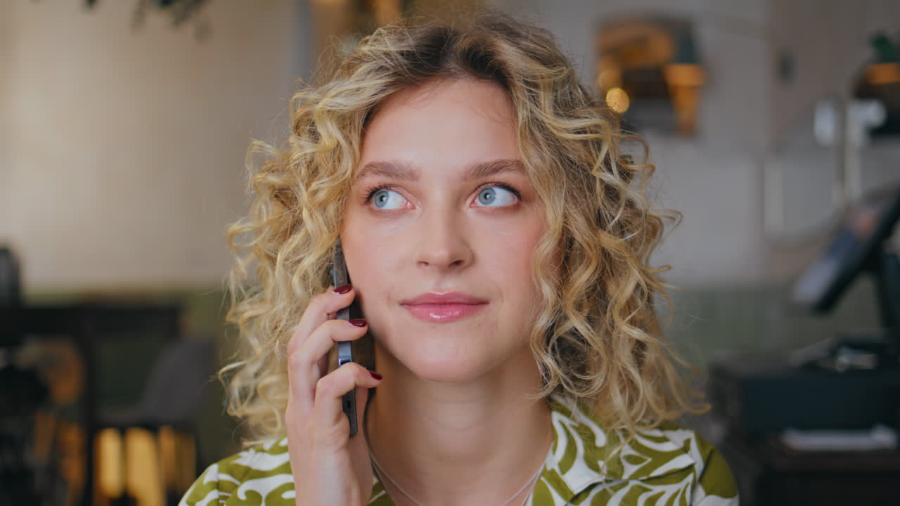 Dreamy girl speaking mobile phone waiting meeting in modern cafe closeup