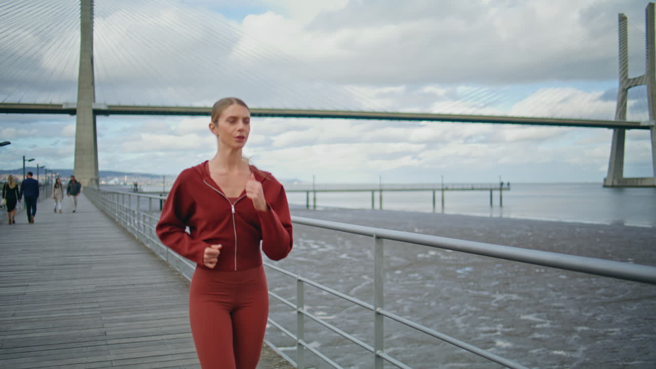 Fit girl running pier at seaside. Tired athlete taking break after cardio sprint