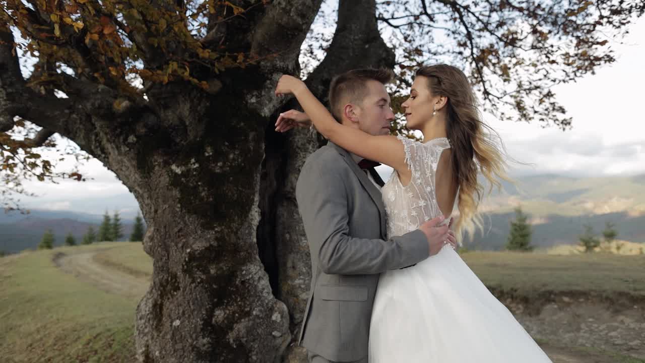 Dejlige unge nygifte brud og gom omfavner på en bjergskråning, lykkeligt bryllupspar familie forelsket