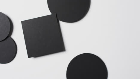 video of close up of square and circles of black paper and copy space on white background