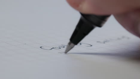 close-up macro shot of a ballpoint pen writing in a blank notebook