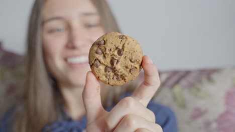 Mujer-Feliz-Sosteniendo-Una-Deliciosa-Galleta-De-Chocolate,-Vista-Frontal-Cercana