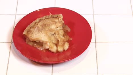 una rebanada recién horneada de tarta de manzana al vapor en un plato rojo